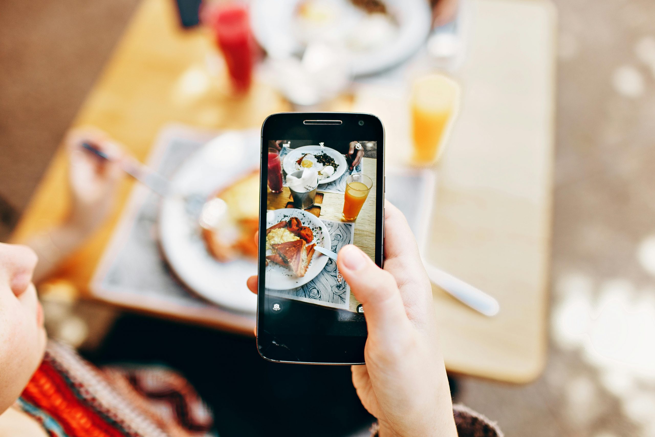 Overhead view of a person photographing a colorful brunch spread with a smartphone.