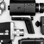Flat lay of assorted vintage video cameras in black and white photography.